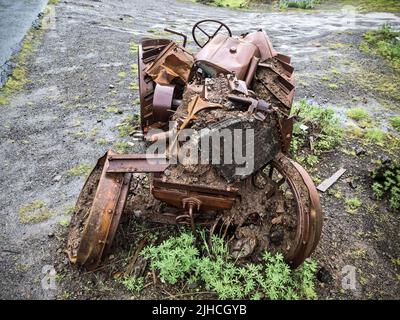 Un trattore abbandonato molto tempo fa e completamente coperto di ruggine. Foto Stock