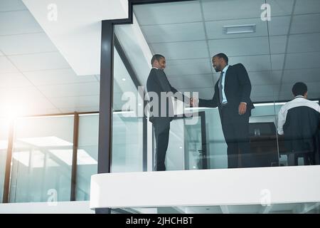 Im contento che tu possa unirti a noi. Inquadratura ad angolo basso di due uomini d'affari aziendali che si scuotono le mani durante una riunione nella sala riunioni. Foto Stock