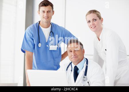 Forniscono la migliore assistenza sanitaria possibile. Ritratto di tre medici professionisti che lavorano insieme su un computer portatile. Foto Stock