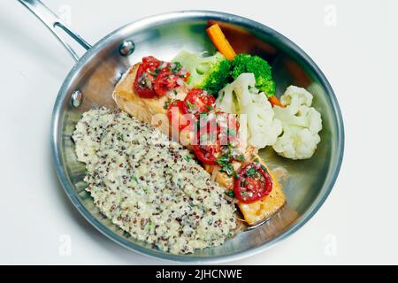 pesce di salmone scottato in padella con quinoa cremosa, pomodoro fresco e verdure a vapore Foto Stock