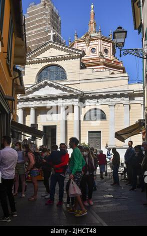 La gente si è schierata di fronte ad un panificio per acquistare la focaccia ligure con la Basilica dei Santi Gervasio e Protasio sullo sfondo, Rapallo, Genova Foto Stock