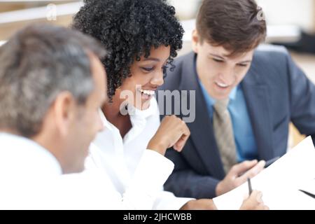 Controllo attraverso il loro programma. Un gruppo diversificato di uomini d'affari che si occupano di lavoro cartaceo durante una riunione. Foto Stock