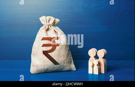 Figurine di famiglia e borsa di soldi indiana della rupia. Budget per famiglie. Entrate, spese. Condizioni favorevoli per la crescita della popolazione. Dati anagrafici. Investimenti in hu Foto Stock
