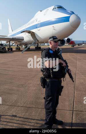 RAF Fairford, Gloucestershire, Regno Unito. 17th Lug 2022. Uno dei più grandi spettacoli aerei del mondo è tornato dopo una pausa di 3 anni a causa della pandemia che ha portato le forze aeree internazionali, le squadre espositore e le enormi folle nei Cotswolds. I favoriti del RAF come il combattente Typhoon e Red Arrows si sono Uniti visitando i jet fighter, le squadre, gli aerei da trasporto e gli elicotteri dall'Europa e dagli Stati Uniti. La polizia armata custodisla US Air Force Boeing e-4 Advanced Airborne Command Post, soprannominato Doomsday Plane. Posto di comando presidenziale per situazioni di guerra. Poliziotto con adesivo per tatuaggio d'aria e pistola Foto Stock