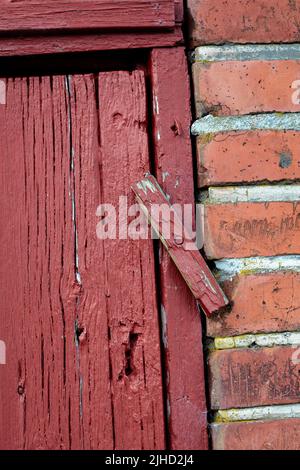 Porte. Primo piano di una vecchia porta di legno rosso in un edificio in mattoni a faccia, molto probabilmente una casa in un quartiere residenziale. Un blocco a scatto su una via d'ingresso. Foto Stock