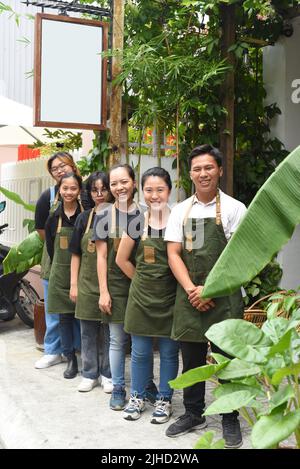 Il personale della caffetteria vietnamita sorride e si alza insieme contro un caffè Foto Stock