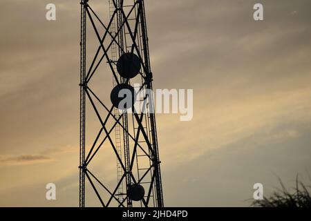 Silhouette di una torre telefonica al tramonto cielo arancione Foto Stock