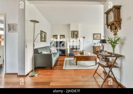 Comodi divani e tavolo in legno posto vicino a piante in vaso contro la finestra nel soggiorno dell'appartamento moderno Foto Stock