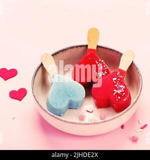 Diversi tipi di gelato a forma di popsicle su sfondo rosa. Atmosfera estiva. Foto Stock