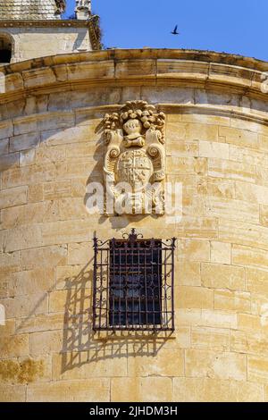 Stemma sulla facciata della vecchia chiesa in pietra accanto alla finestra con bar, Torrelaguna Madrid. Foto Stock