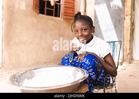 Povera ragazza africana che mangia riso bianco senza medicazione, verdure o carne; importanza di cibo di base come pane, riso e patate in cou sviluppo Foto Stock