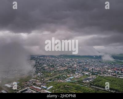 Volare attraverso le nuvole spesse. Nuvole di pioggia nel cielo. Cumulus nuvole, meteorologia e studi sul clima. Foto della città dall'altezza delle nuvole, aer Foto Stock