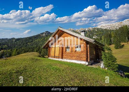 Dolomiti, Italia - Chalet in legno tradizionale nelle Dolomiti in una giornata estiva soleggiata con cielo blu e nuvole Foto Stock