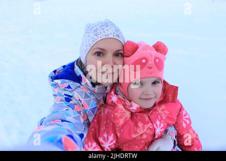 Ritratto mamma e figlia in giro un tubing in inverno. La famiglia trascorre del tempo fuori in inverno. Sled giochi. Verticale in primo piano. Selfie Foto Stock