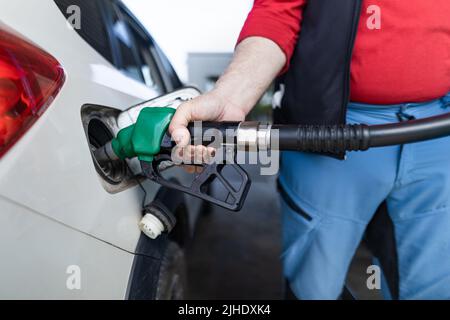 Lavoratore senior in piedi sulla stazione di servizio e auto di rifornimento. Foto Stock