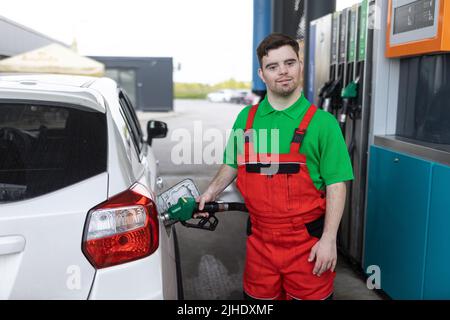 Down sindrome uomo dipendente rifornimento auto presso la stazione di benzina. Foto Stock