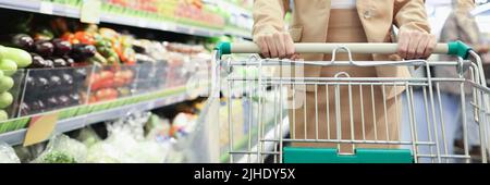 Donna sorridente con carrello di shopping in supermercato acquistare alimentari alimentari Foto Stock