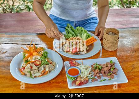 Thai donna che mangia somatam pu pla ra con riso appiccicoso Foto Stock