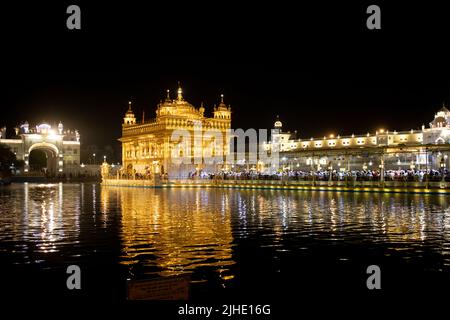 Amritsar, Punjab, India - Maggio 20th 2022: Pellegrini riuniti al Tempio d'Oro di Amritsar illuminato di notte Foto Stock