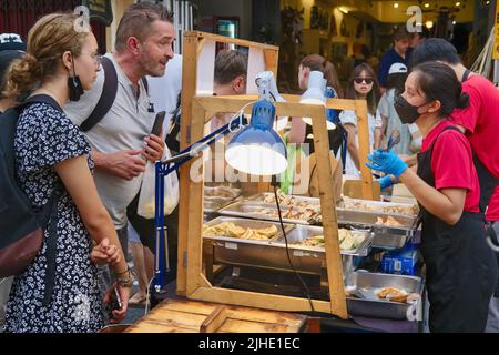 I turisti occidentali in una bancarella di spuntini in Domenica Walking Street Market, Thalang Road, nella zona della Città Vecchia di Phuket Town (Chinatown), Phuket, Thailandia Foto Stock