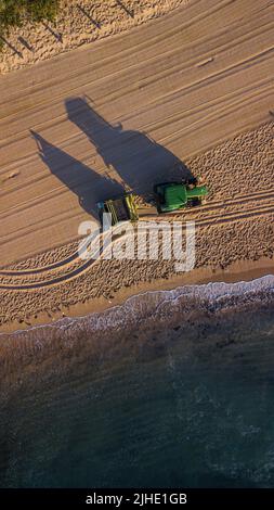 Una vista dall'alto del drone aereo di un trattore che pulisce su una spiaggia di sabbia a Maroubra, Sydney, Australia Foto Stock