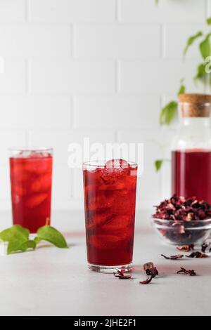 Una bevanda rinfrescante a base di foglie di ibisco essiccato e ghiaccio in un bicchiere. Foto Stock