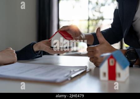 Azienda immobiliare per comprare case e terreni stanno consegnando chiavi e case ai clienti dopo aver accettato di fare un accordo di acquisto casa e fare un Foto Stock