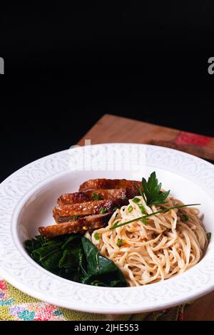 Cucina Asiatica concetto biologico fatto in casa Alkaline noodles con anatra arrosto su tavola di legno con sfondo nero con spazio copia Foto Stock