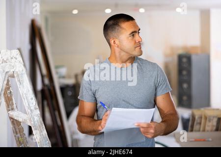 Man Construction Manager controlla la documentazione del progetto Foto Stock