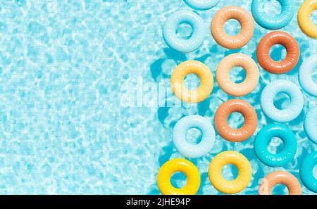 3D rendering vista dall'alto di variopinti anelli gonfiabili galleggianti nell'acqua della piscina all'aperto nella soleggiata giornata estiva Foto Stock