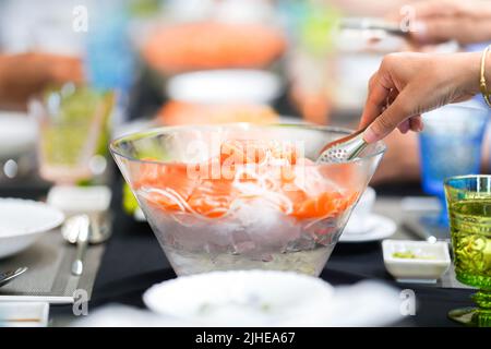 Salaryman sta consumando una portata Giapponese presso il ristorante di alto livello, che viene servito con salmone, sushi, sashimi e edamame sul grande tavolo da pranzo Foto Stock