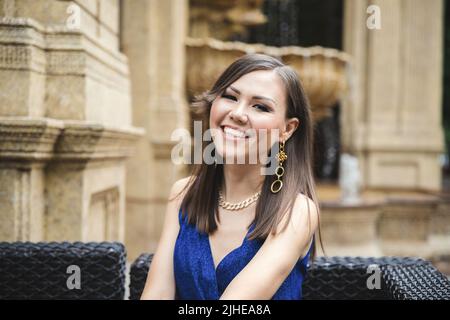 Donna asiatica piuttosto sorridente in abito blu ritratto esterno Foto Stock