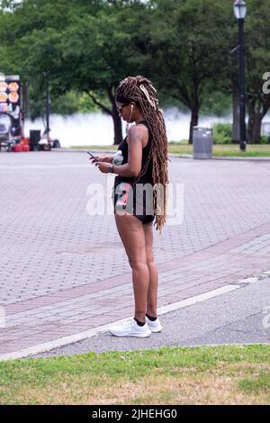 Donna vestita di abbigliamento sportivo e con prolunghe dei capelli molto lunghe. Al Flushing Meadows Corona Park a Queens, New York. Foto Stock
