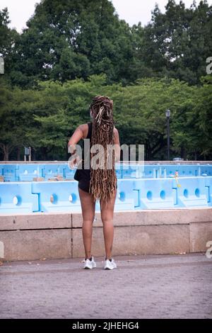 Donna vestita di abbigliamento sportivo e con prolunghe dei capelli molto lunghe. Da dietro. Al Flushing Meadows Corona Park a Queens, New York. Foto Stock