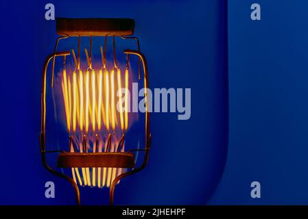 filamento di tungsteno di lampada ad incandescenza ad alta potenza su sfondo blu da vicino con copyspace Foto Stock