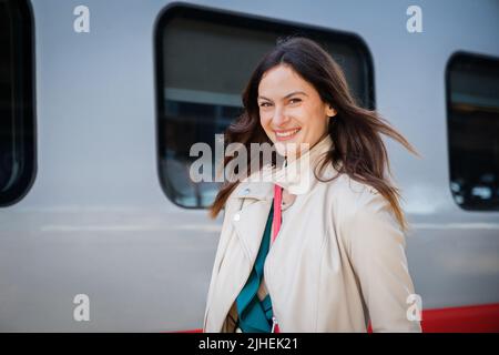 Ritratto di una donna in viaggio d'affari che cammina in una stazione ferroviaria o aeroporto andando al cancello d'imbarco con bagaglio a mano Foto Stock