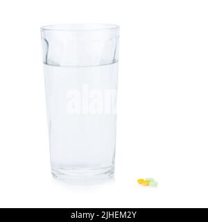 Acqua vetro. Pillola e compressa colore giallo e verde. Prendere un medicinale. Isolato su sfondo bianco Foto Stock