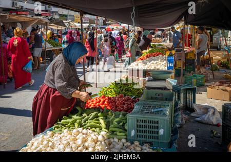 Una donna acquista verdure in una stalla del suk domenicale, un mercato settimanale a Sousse, Tunisia. Foto Stock