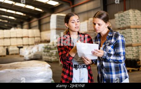 Donna di vendita che aiuta l'acquirente femmina che controlla l'elenco degli ordini Foto Stock