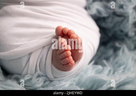 ThSoft piedi di un neonato in una coperta bianca e su sfondo blu Studio Macro fotografia. Felicità della donna. Foto Stock