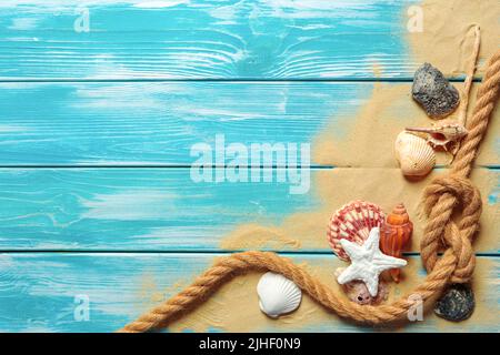 Corda di mare con molte diverse conchiglie di mare sulla sabbia di mare su  un blu sullo sfondo di legno. Vista superiore Foto stock - Alamy
