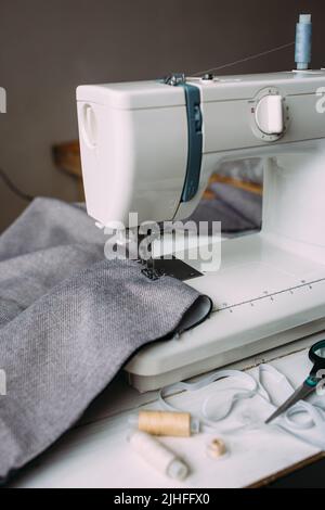 Macchina per cucire, accessori e tessuto. Processo di cucito creativo e accogliente a casa Foto Stock