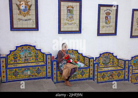 Passeggiata Paseo de Canarias con piastrelle in ceramica, donna delle canarie seduta su panca e maglie artful, Firgas, Grand Canary, Isole Canarie, Spagna, Europa Foto Stock