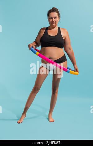 Collage concettuale con giovane donna più-size con gambe snelle facendo esercizi con hula hoop. Perdita di peso, idoneità, alimentazione sana, motivazione Foto Stock