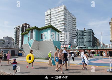 La gente che cammina oltre la casa capovolta in spiaggia di Brighton Heatwave 2022 Foto Stock