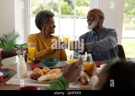 Immagine di una coppia di anziani afro-americani allegri che tostano con succo Foto Stock