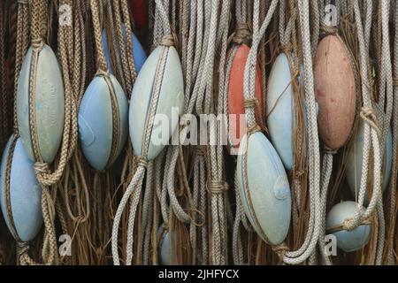 vecchie corde con galleggianti di rete di pesca color pastello che pendono da vicino Foto Stock