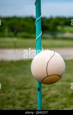 Tetherball seduto inattivo accanto al palo in un cortile. Foto Stock