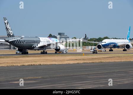 Farnborough, Hampshire, Regno Unito. 18 luglio 2022. La fiera commerciale delle tecnologie aerospaziali civili e militari è tornata dopo la pausa dovuta alla pandemia di covid con le principali società mondiali di aviazione e tecnologia spaziale che espongono i loro prodotti in volo e a terra. Airbus A350-900 di fronte a un Boing 777-9 sulla pista prima delle loro esibizioni di volo. Airbus e Boeing sono i due principali rivali nel settore degli aerei di linea Foto Stock