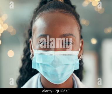 Faccia anteriore del medico che indossa una maschera covid. Medico afroamericano primo piano in ufficio. Ritratto di medico afroamericano nella sua clinica. Verticale Foto Stock